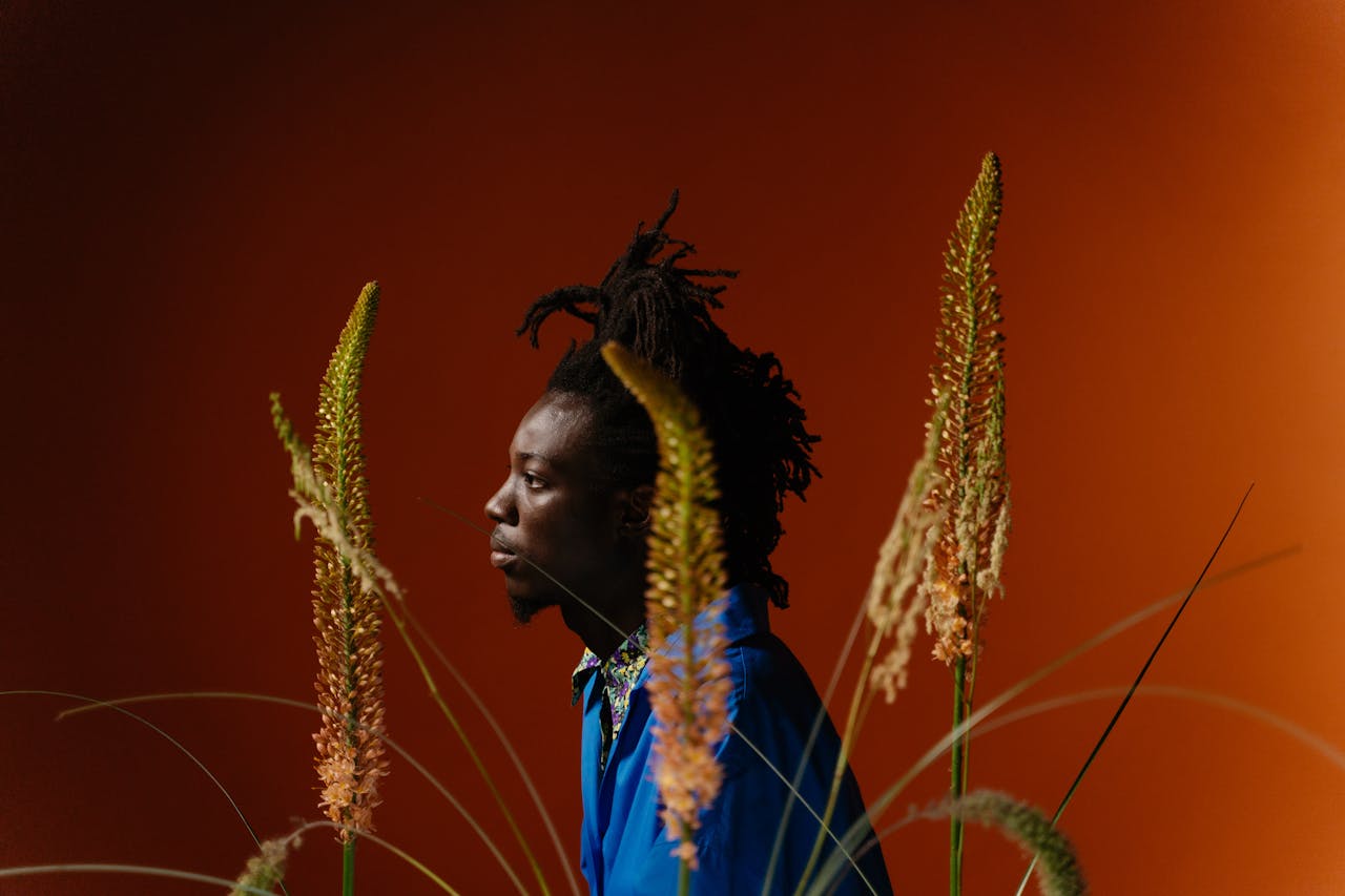 Artistic side profile portrait of a stylish man with dreadlocks in a studio.